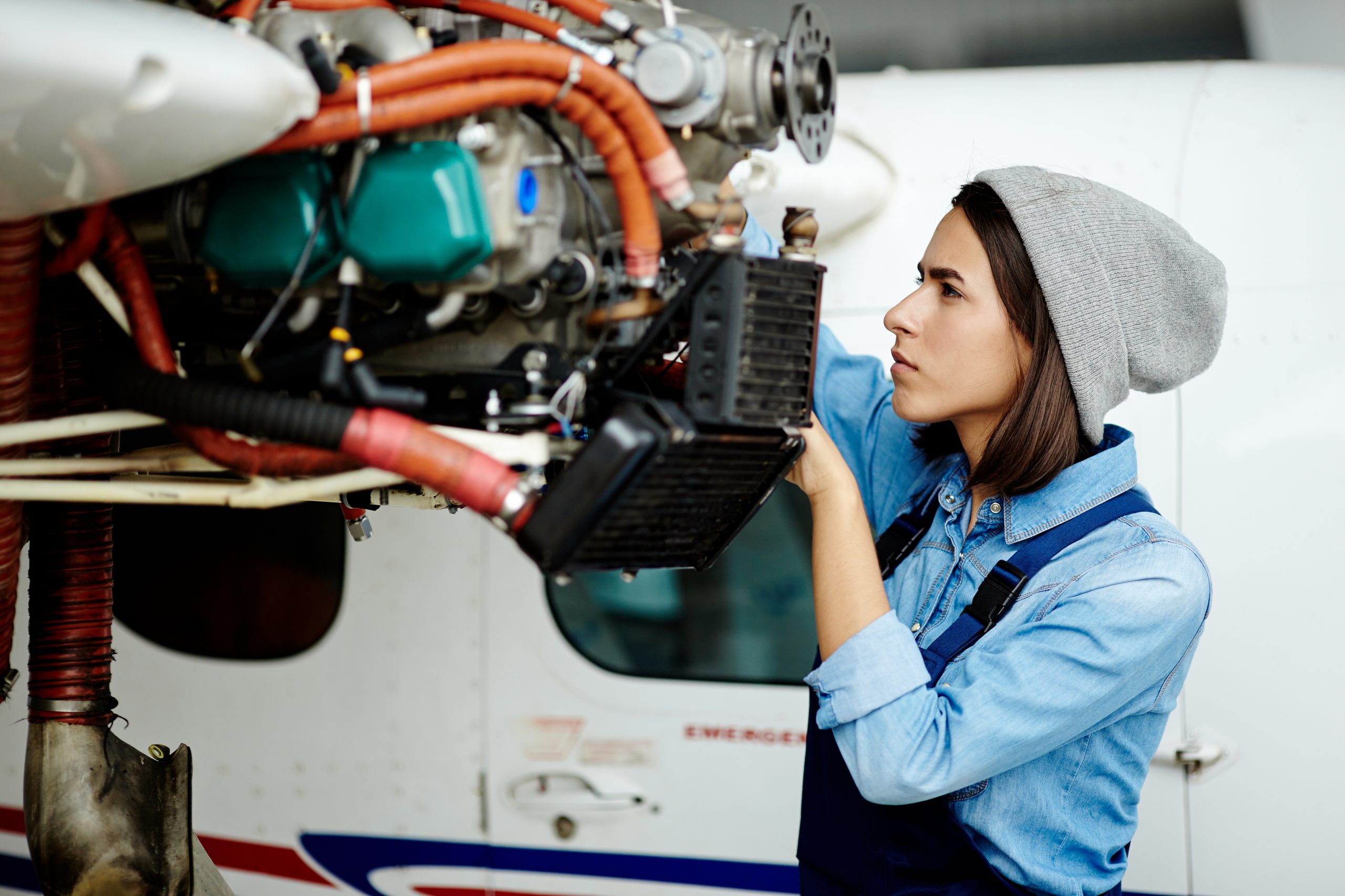 Female caucasian aircraft mechanic working on plane