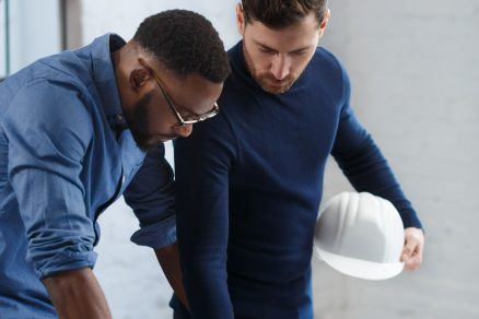 Black male and caucasian male looking at blueprint