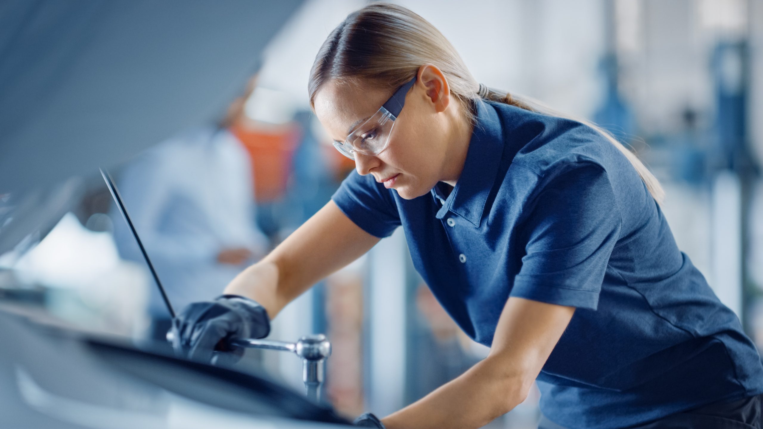 Caucasian female automotive technician working on engine