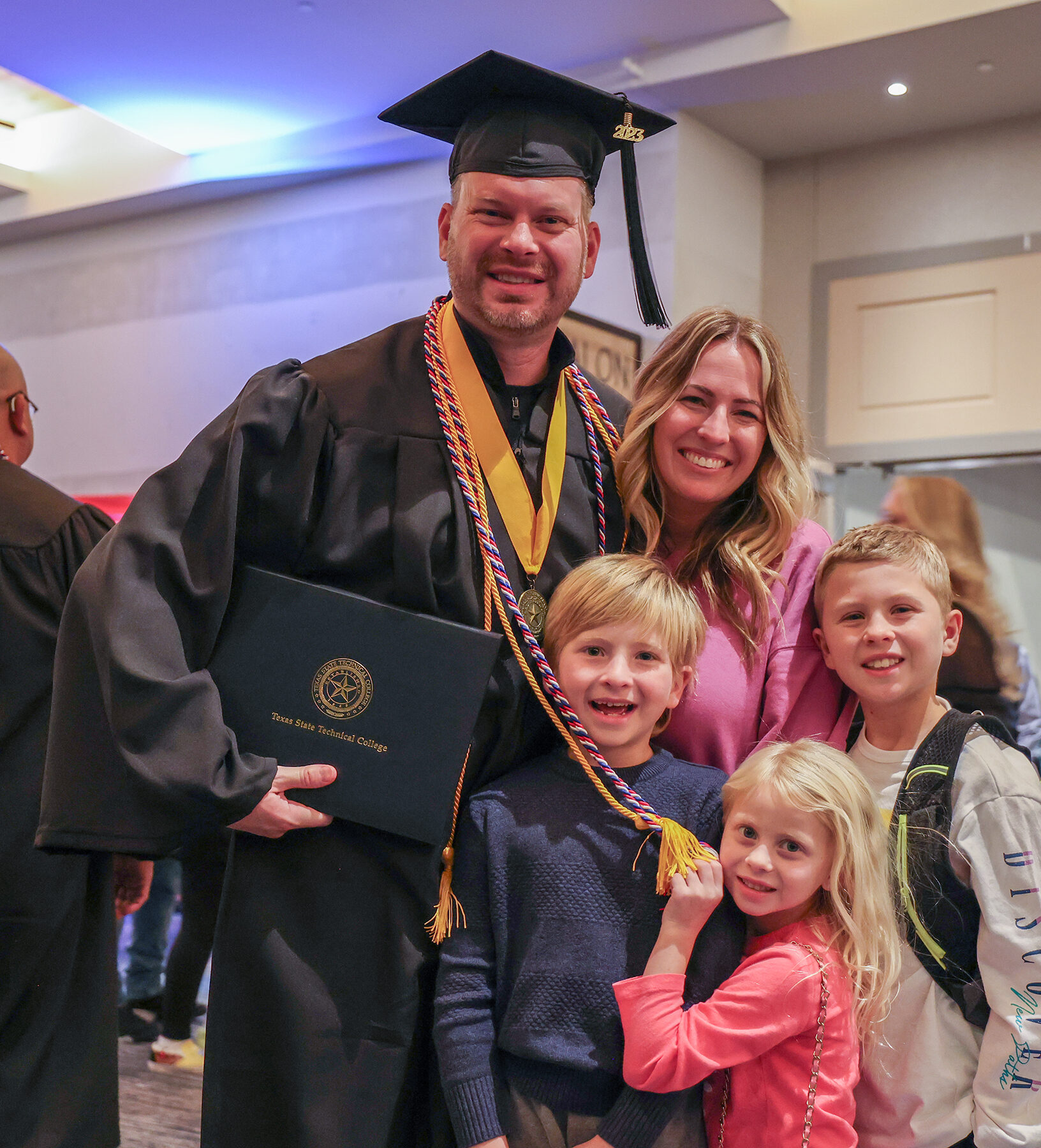 A TSTC graduate is happily surrounded by his wife and three children after the Fall 2023 ceremony.