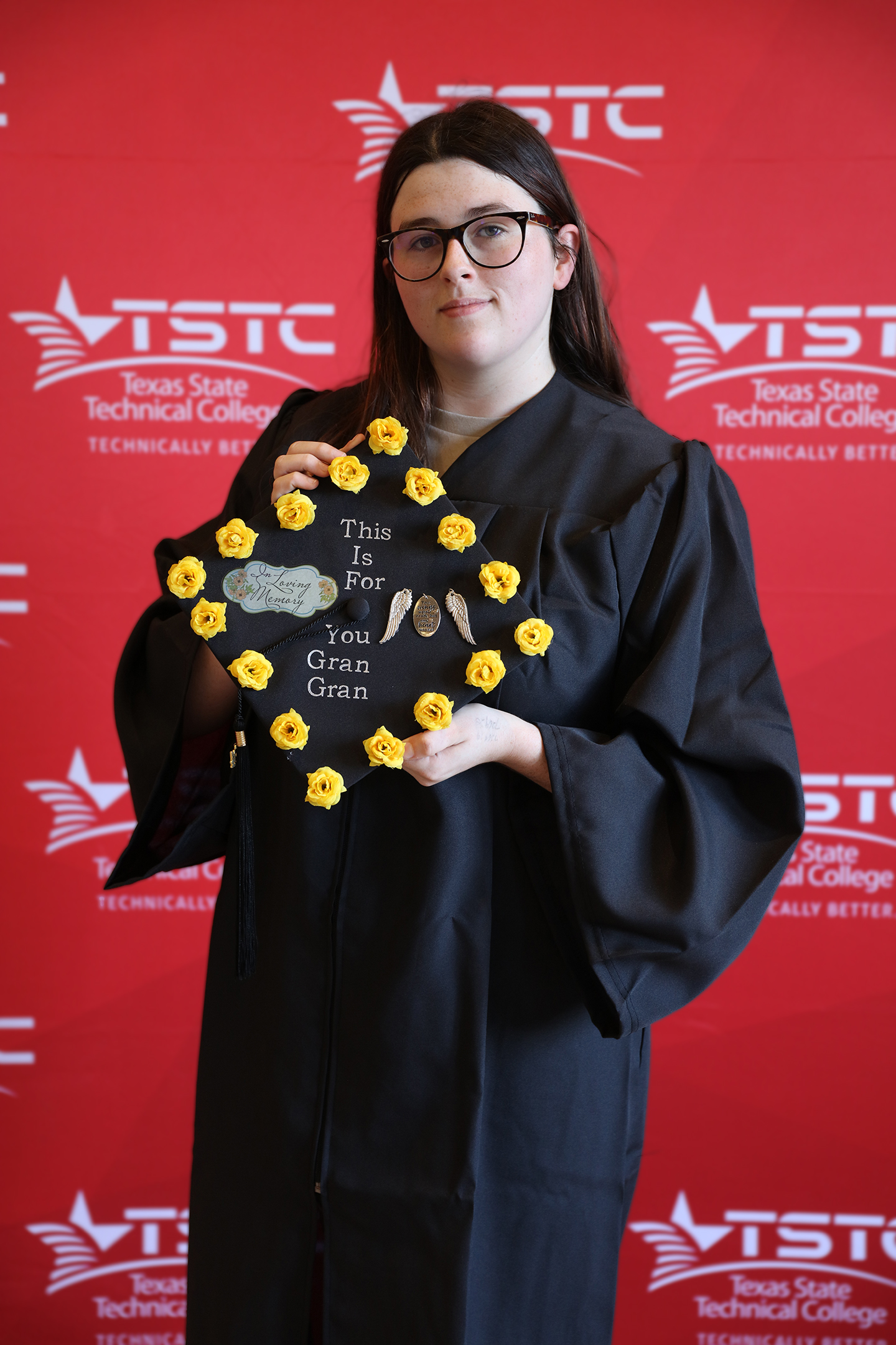 A female graduate holds up her decorated graduation cap at the Summer 2024 commencement ceremony in Marshall, Texas.