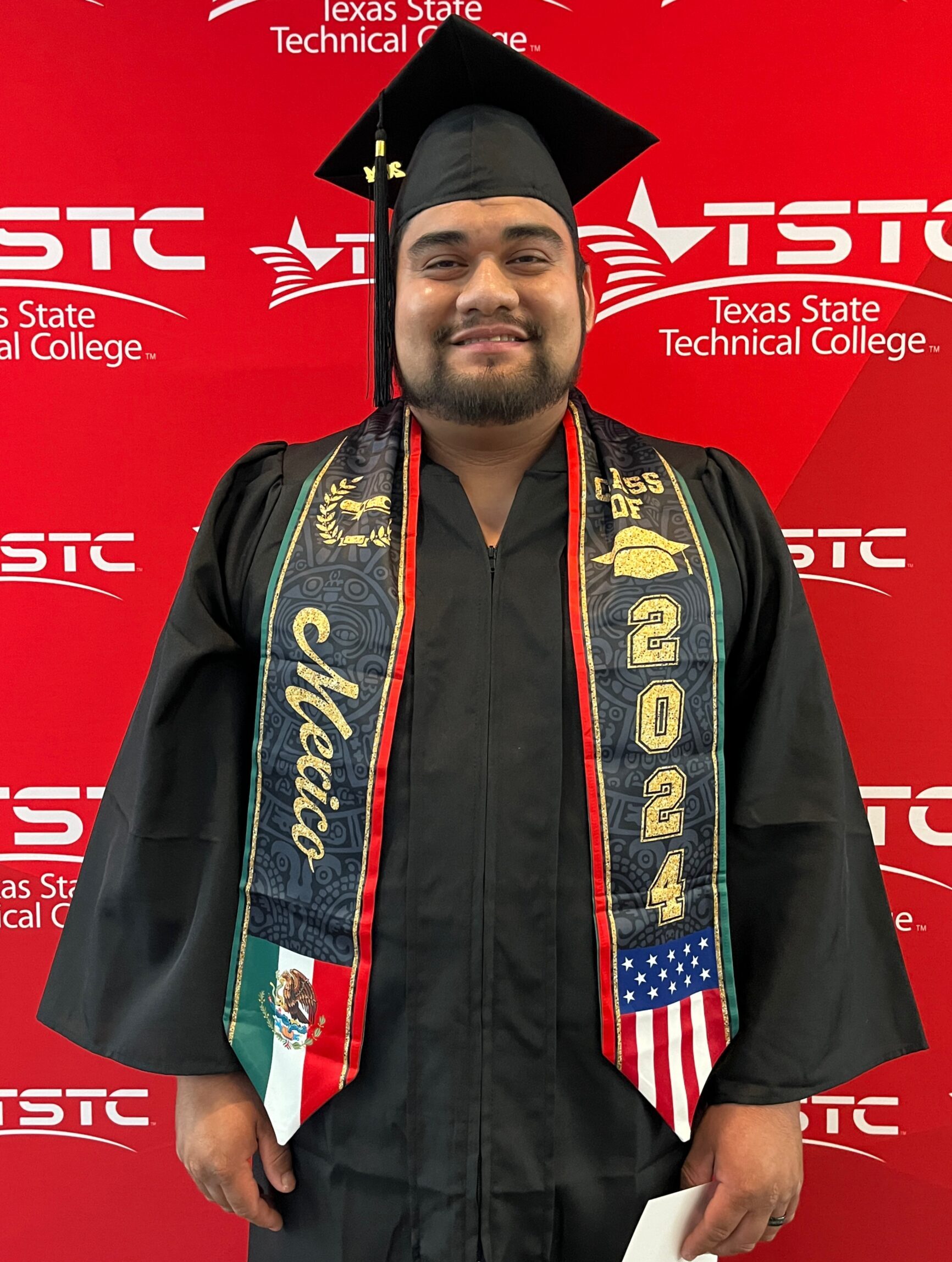 A male graduate posing in his cap and gown at the Summer 2024 commencement ceremony in North Texas.