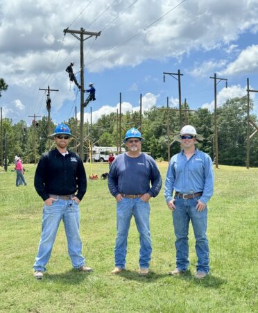 TSTC graduate Ryan Hall (right) recently visited the Marshall campus and reunited with TSTC Electrical Lineworker and Management Technology instructors Samuel Roberts (left) and Mark Bayliss (center), with whom he previously worked at Southwestern Electric Power Co. TSTC lineworker students can be seen in the background on the program’s practice utility poles. (Photo courtesy of TSTC.)