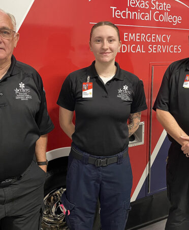 three people standing in front of ambulance
