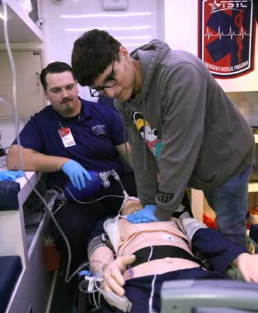 Luis Rodriguez (right), a junior at San Benito High School, practices CPR on a medical manikin in the EMS program’s ambulance simulator at TSTC, while TSTC EMS student James Johnson observes him during the MAARS program held at the Harlingen campus.