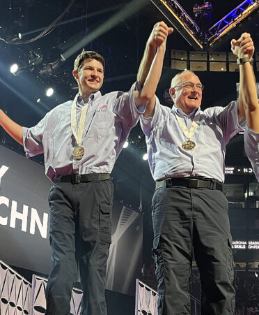 two men in blue shirts on medal podium