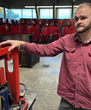 man in red shirt standing in welding lab