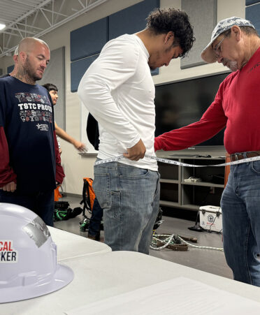 man in red shirt measuring waste of man in white shirt