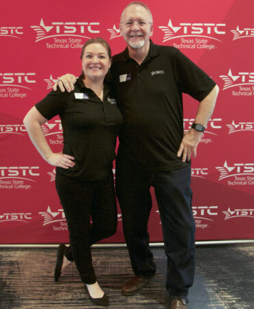 Audrey Davis standing with her father Duane Davis in front of a red TSTC banner.