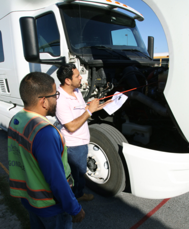 Carlos Mercado (right), a student driver in TSTC’s Professional Driving Academy, identifies the fluid levels in a coolant tank for his pre-trip inspection with CDL trainer Isaac Gonzalez.