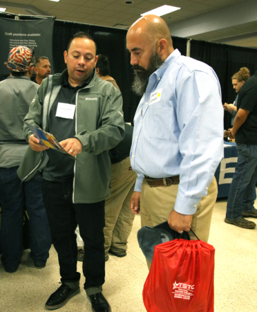 Daniel Campos (right), a TSTC Electrical Lineworker and Management Technology graduate, visits with Carlos Gabriel Cambrelen, workforce development manager for Kiewit Corp., at the recent Fall 2024 Industry Job Fair held at TSTC’s Harlingen campus.