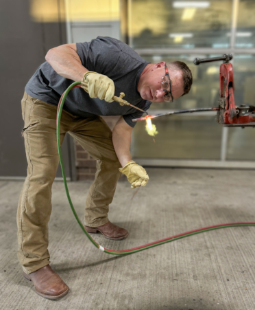 Jason Wehring leans to the side to view the flame impact on his brazing process.