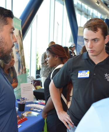 man in blue shirt talking to man in black shirt