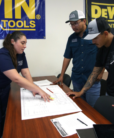 Cecilia Espinosa (left), a Building Construction Technology instructor at TSTC’s Harlingen campus, explains electrical plans for a commercial building to students Luis Escobedo (center) and Zac Pena during a recent class lecture.