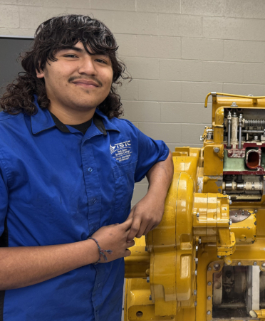 man in blue shirt standing next to diesel engine