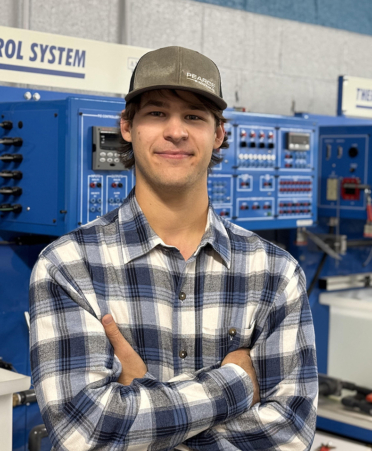 Man in plaid shirt standing in front of equipment.