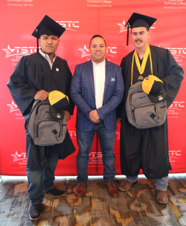 Matthew Blanco (left) and Skylar Jensen (right), TSTC Electrical Lineworker and Management Technology 2024 graduates, stand with Carlos Gabriel Cambrelen, workforce development manager for Kiewit Corp., which has hired both graduates for new jobs with Kiewit.