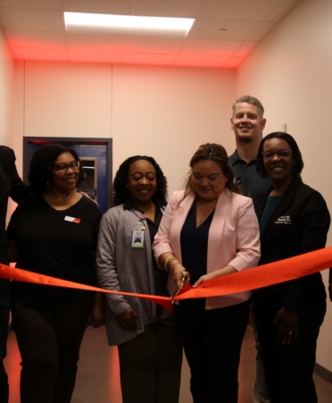 A red ribbon is cut in with four people standing around it.