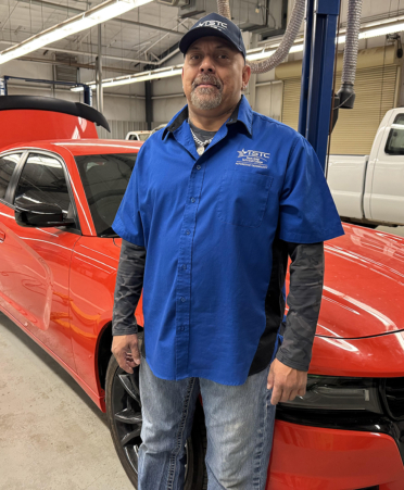 man in blue shirt standing in auto shop