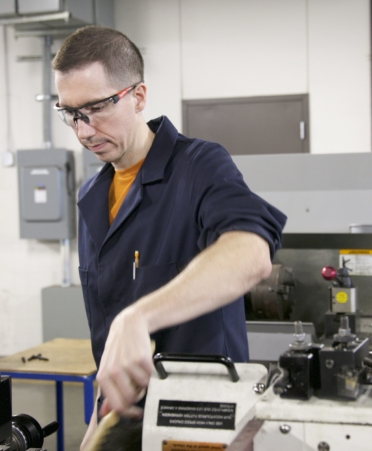 Precision Machining Technology student Ethan Williams brushes off a lathe during a recent lab session.